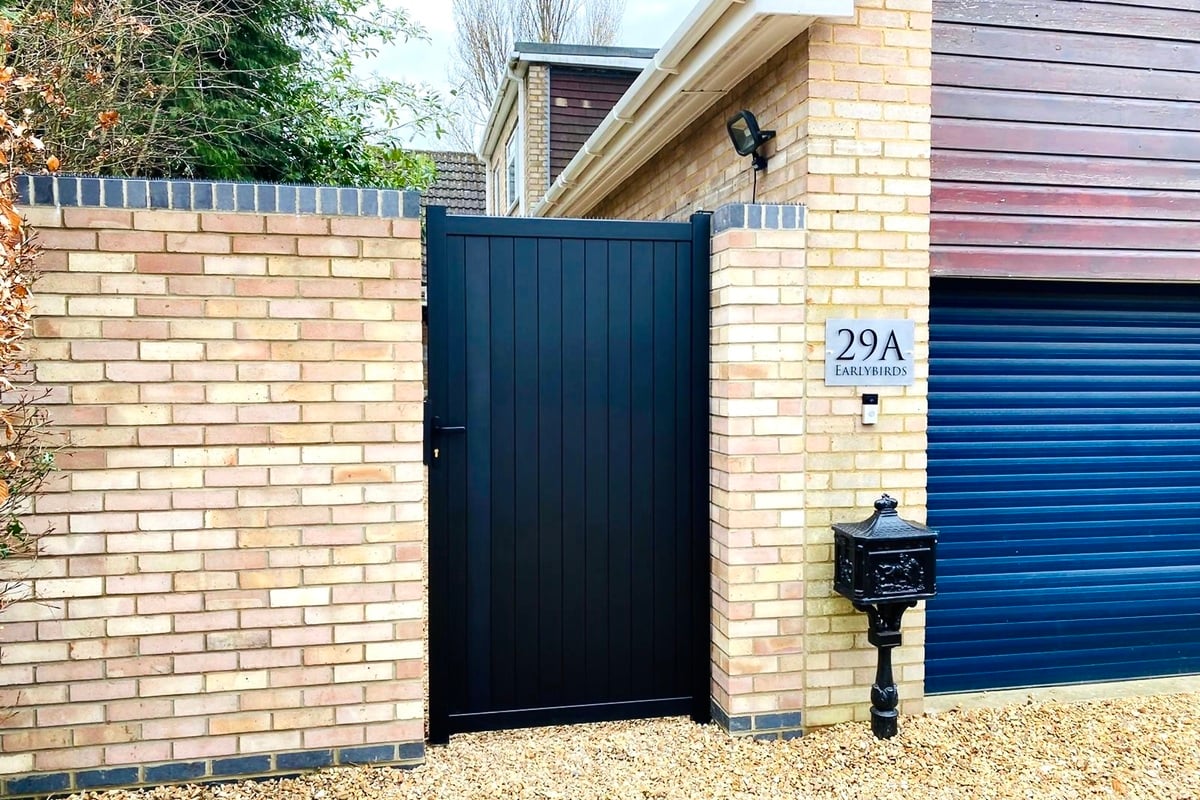 Black aluminium pedestrian gate with solid infill,vertical slats and a flat top in-situ. image