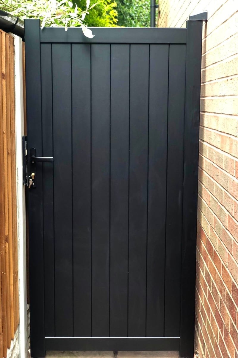 Black aluminium pedestrian gate with solid infill,vertical slats and a flat top in-situ. image